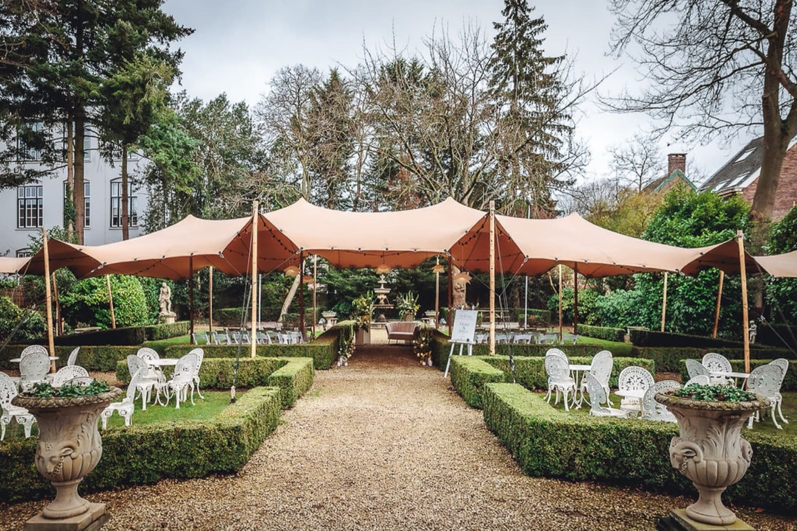 Tuin van Villa 1855 met tentdoeken en pad door de hagen